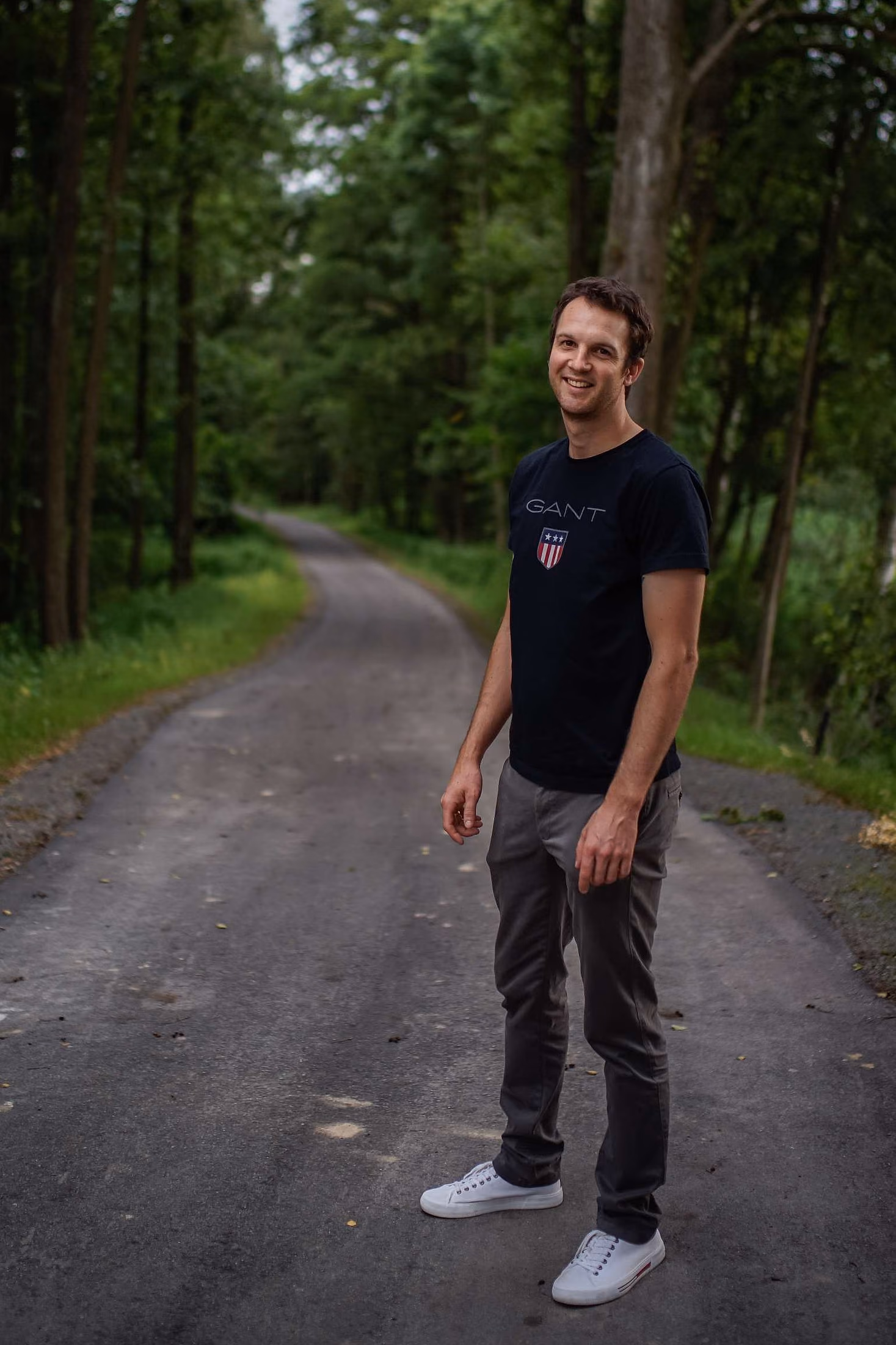Marcel Frölich steht auf einem Waldweg und lacht in die Kamera